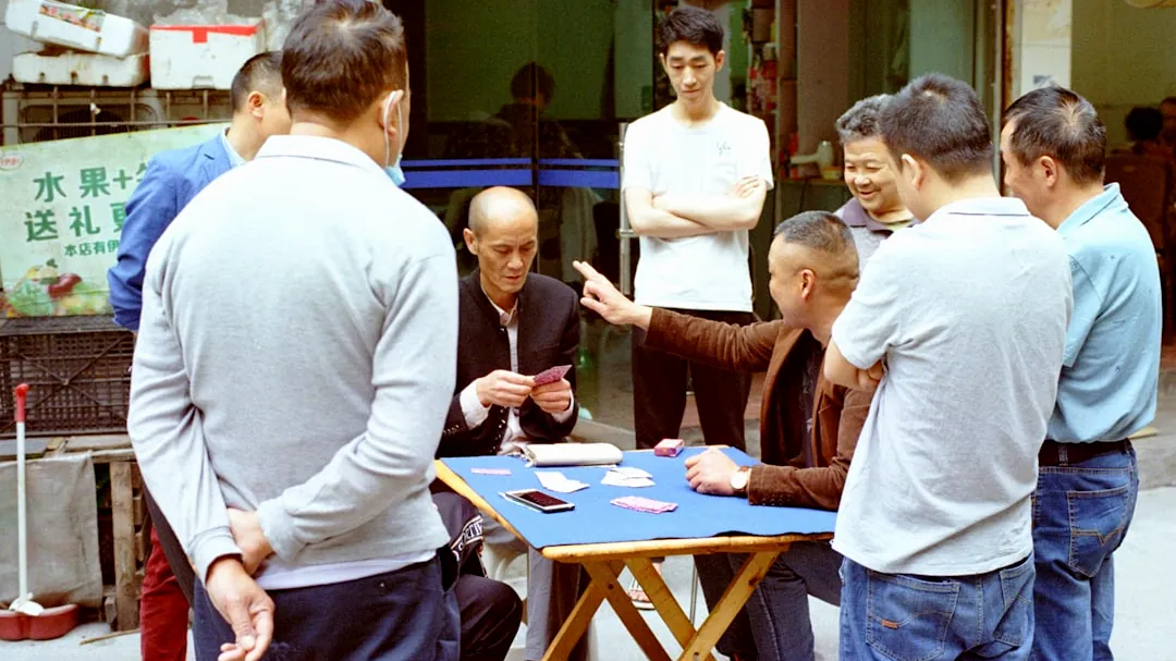 a group of men standing around a table playing cards