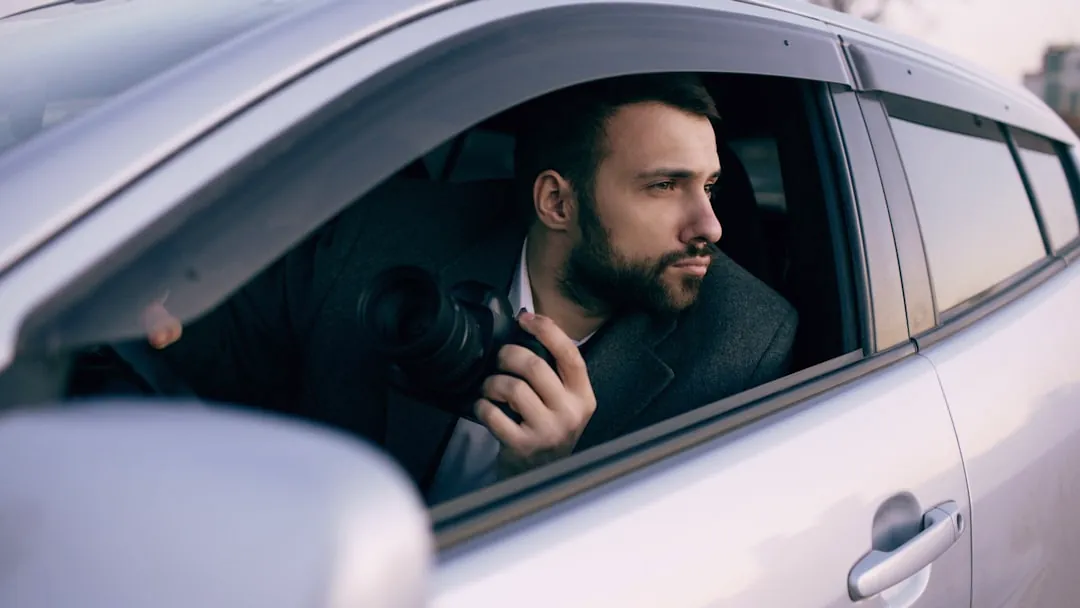 Man in suit holding camera in car