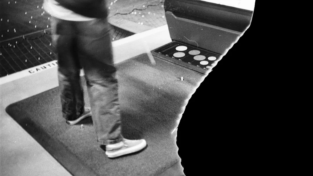 Person standing on a mat near an arcade game