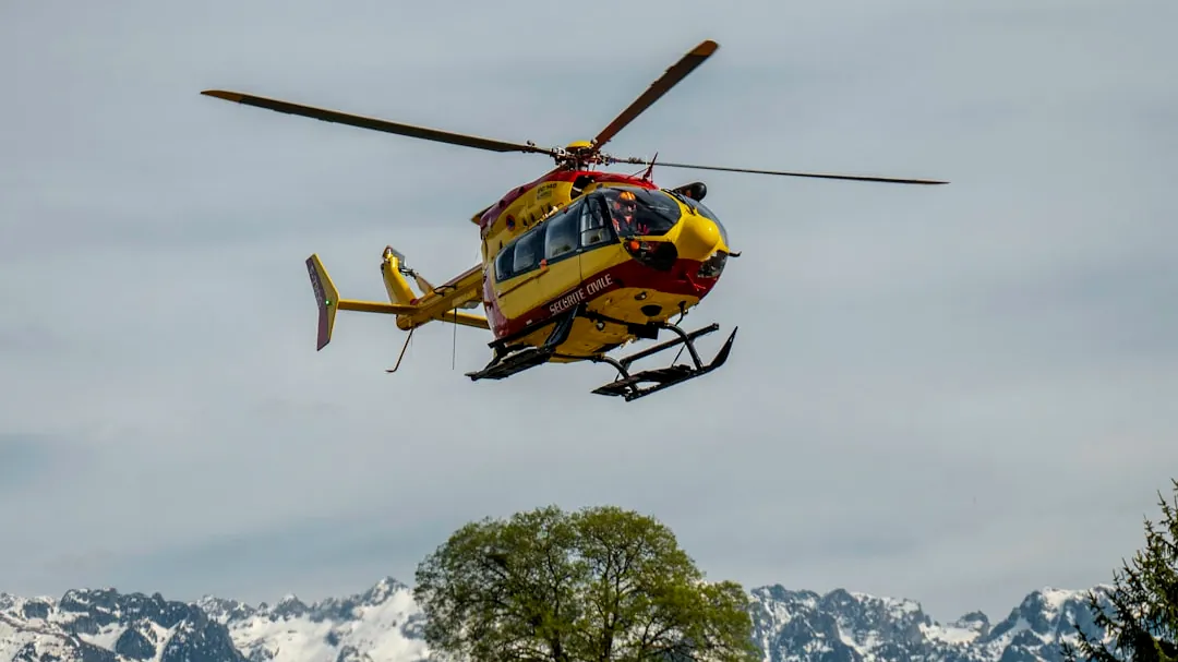 yellow and black helicopter flying over snow covered mountain during daytime