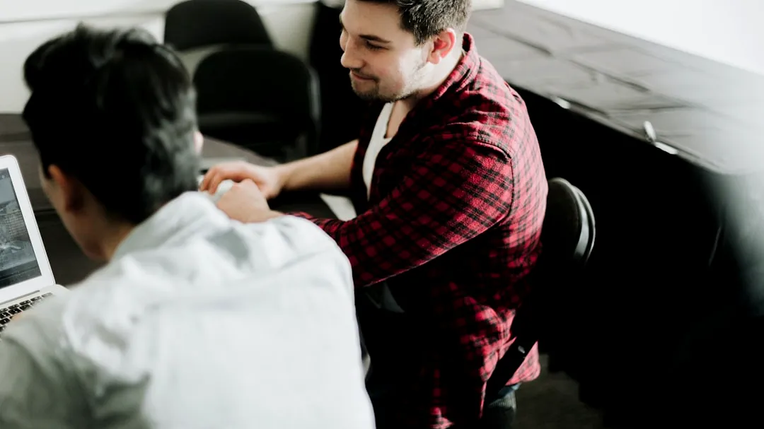 a man sitting at a desk shaking hands with another man