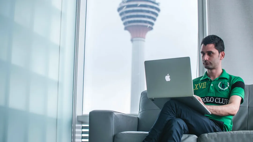 man sitting on sofa holding MacBook